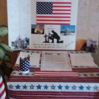 A patriotic table display featuring an American flag and memorial items.