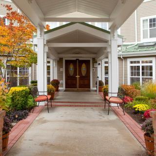 A welcoming entrance with autumnal decor and outdoor seating.