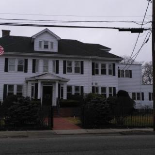 A large residential house with a white exterior and dark shutters.
