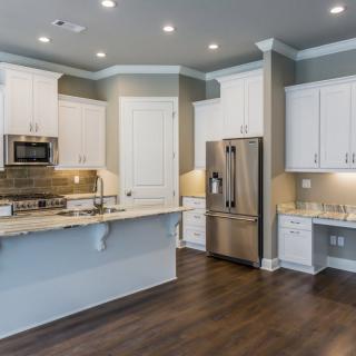 A modern kitchen featuring white cabinets and stainless steel appliances.