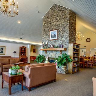 A cozy lounge area featuring a stone fireplace, comfortable seating, and elegant chandeliers.