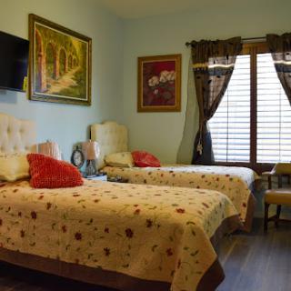 A cozy bedroom featuring two beds, decorative artwork, and warm lighting.
