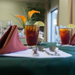 A neatly set dining table with glasses of iced tea and lemon slices.