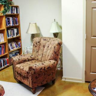A cozy reading corner with an armchair and a bookshelf filled with books.