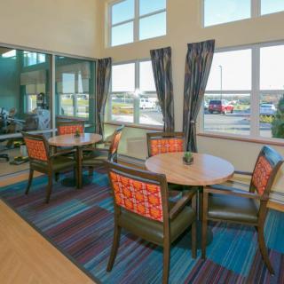 A cozy dining area with tables, chairs, and large windows letting in natural light.