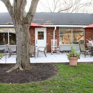 A backyard with a patio area featuring outdoor seating and potted plants, set against the backdrop of a house.