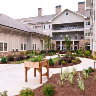 A beautifully landscaped courtyard with a garden and pathways in front of a residential building.