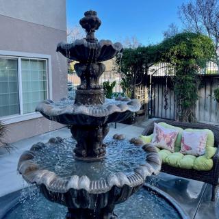 A serene outdoor patio with a decorative fountain and comfortable seating area.