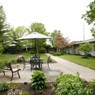 A serene outdoor seating area surrounded by lush greenery and colorful flowers.