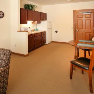 A cozy apartment interior featuring a kitchenette and dining area with wooden cabinets.