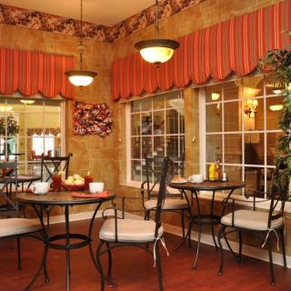 A cozy cafe interior with tables and chairs near large windows.