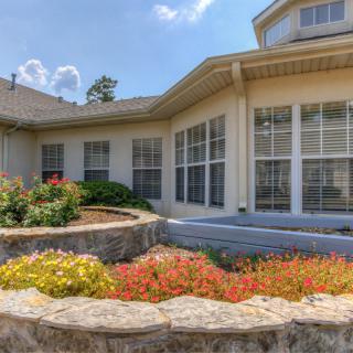 A view of a building with large windows and a beautifully landscaped garden in the foreground.