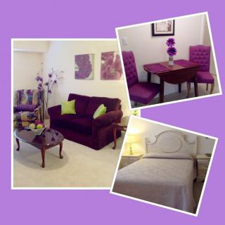 A cozy living space with a purple-themed decor featuring a sofa, dining area, and bedroom.