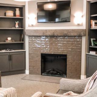 A modern living room with a central fireplace, built-in shelves, and a wall-mounted television.