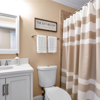 A neatly organized bathroom with a striped shower curtain and a vanity with a mirror.