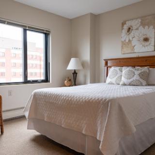 A cozy and well-decorated bedroom featuring a comfortable bed, soft lighting, and natural light from the window.