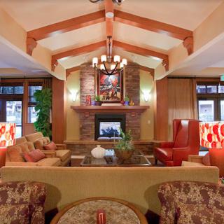 A cozy living room with a warm fireplace, comfortable seating, and elegant wood beam ceiling.
