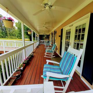 A cozy porch with rocking chairs and ceiling fans, perfect for relaxing on a sunny day.