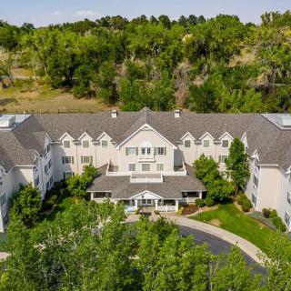 Aerial view of a large mansion surrounded by lush greenery and a landscaped driveway.