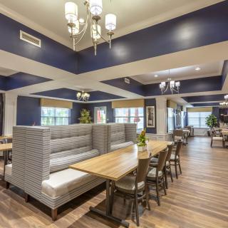 A spacious and elegantly designed restaurant interior featuring booth seating and modern chandeliers.