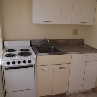 A compact kitchen featuring essential appliances such as a stove and sink, along with storage cabinets.