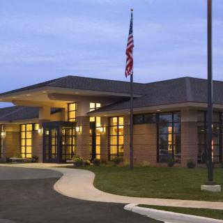 A modern school building with illuminated windows and an American flag in the evening.