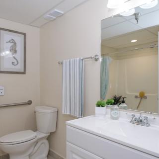 A clean and well-lit bathroom with a toilet, sink, and mirror.