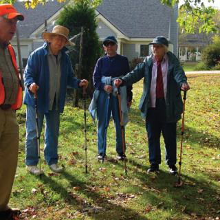 A group of elderly individuals with walking sticks enjoying a sunny autumn day.