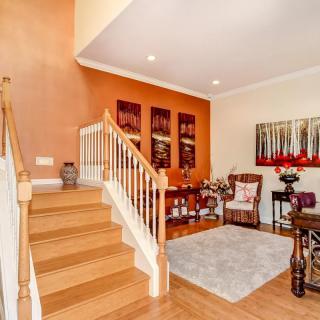 A spacious living area featuring a wooden staircase, elegant decor, and colorful artwork.