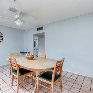 A cozy dining area featuring a wooden table surrounded by chairs, complemented by a ceiling fan and light blue walls.