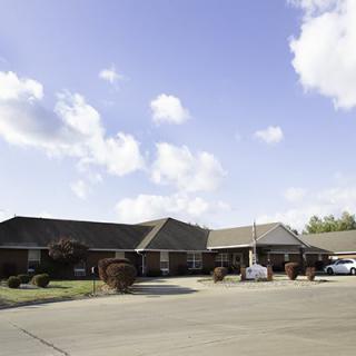 A residential building with a driveway under a partly cloudy sky.