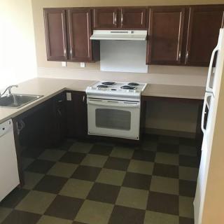 A clean, modern kitchen with dark wood cabinets, an oven, and tiled flooring.