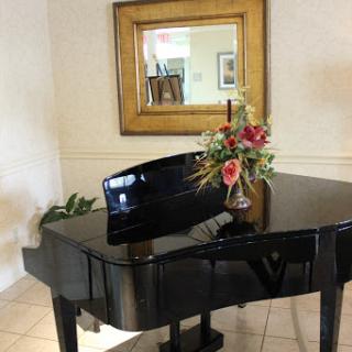 A stylish grand piano accompanied by a beautiful floral arrangement and a decorative mirror.