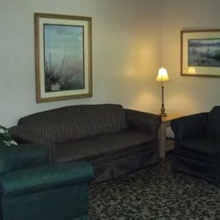 A cozy living room with a sofa, armchairs, and soft lighting from a lamp.