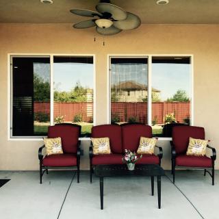 A cozy patio setup with red cushioned chairs and decorative pillows in front of large windows.