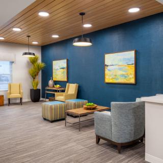 A modern lounge area featuring blue walls, comfortable seating, and vibrant artwork.