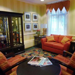 A cozy living room with a red sofa, matching armchairs, and a black cabinet displaying decorative items.