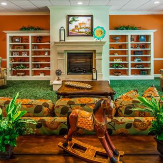 A cozy living room featuring a fireplace, bookshelves, and a charming wooden rocking horse.