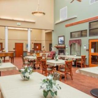 A spacious and well-lit dining area with tables, chairs, and floral decorations.