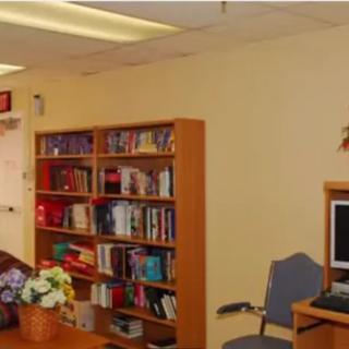 A cozy office space featuring a bookshelf filled with books, a computer desk, and an upholstered chair.
