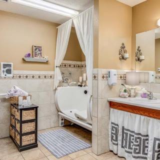 A cozy bathroom featuring a walk-in tub with curtains, a sink with a large mirror, and decorative elements.
