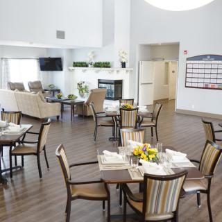 A well-lit community dining and living space with tables, chairs, and a cozy seating area.