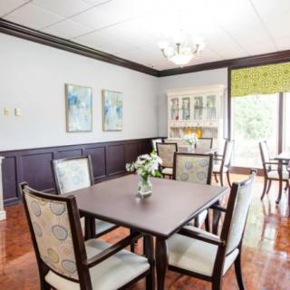 A well-lit dining room with a set of tables and chairs, featuring elegant artwork on the walls.