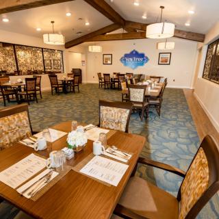 A well-lit dining room with neatly arranged tables and wooden furniture.