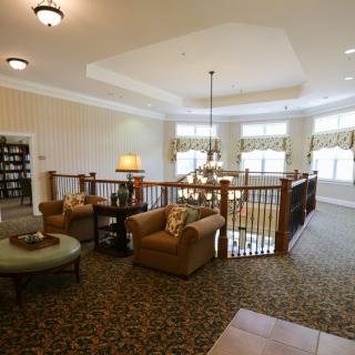 Spacious living area with comfortable seating, large windows, and a chandelier.
