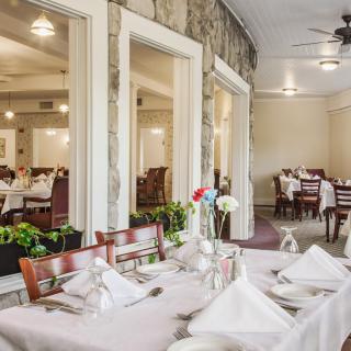 A well-set dining area in a restaurant, featuring neatly arranged tables and chairs with elegant table settings.