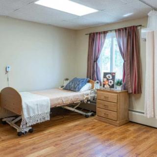A tidy hospital room with a single bed and wooden flooring.