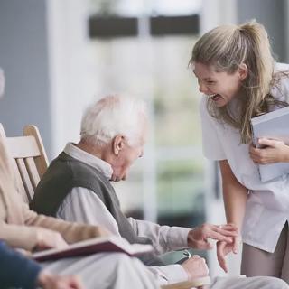 A caregiver is engaging with an elderly person in a nursing home setting.