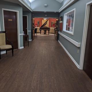 A well-lit hallway featuring a piano and comfortable seating.