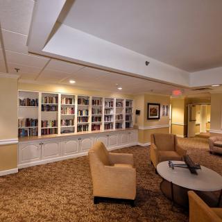 A cozy library seating area with bookshelves, comfortable chairs, and warm lighting.